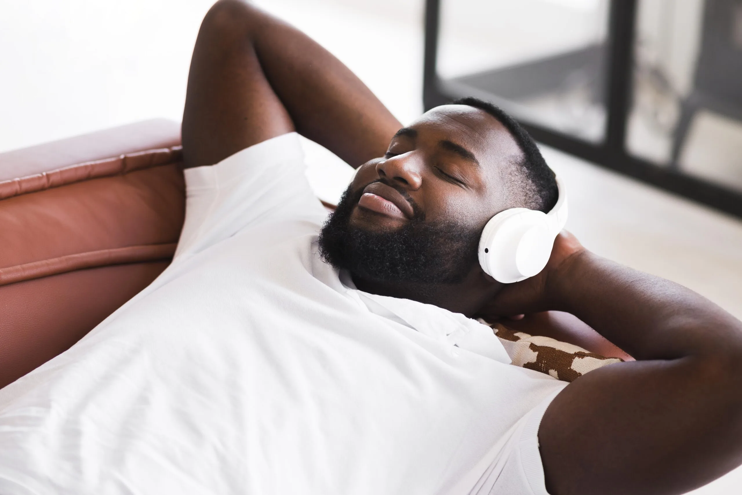 Homme noir détendu écoutant de la musique sur son canapé
